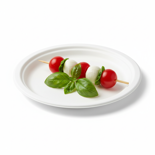 Une assiette ronde biodégradable de 18 cm en fibre de canne, sur laquelle est délicatement posée une brochette apéritive colorée (tomate cerise, mozzarella, basilic), sur un fond blanc épuré mettant en valeur sa texture.