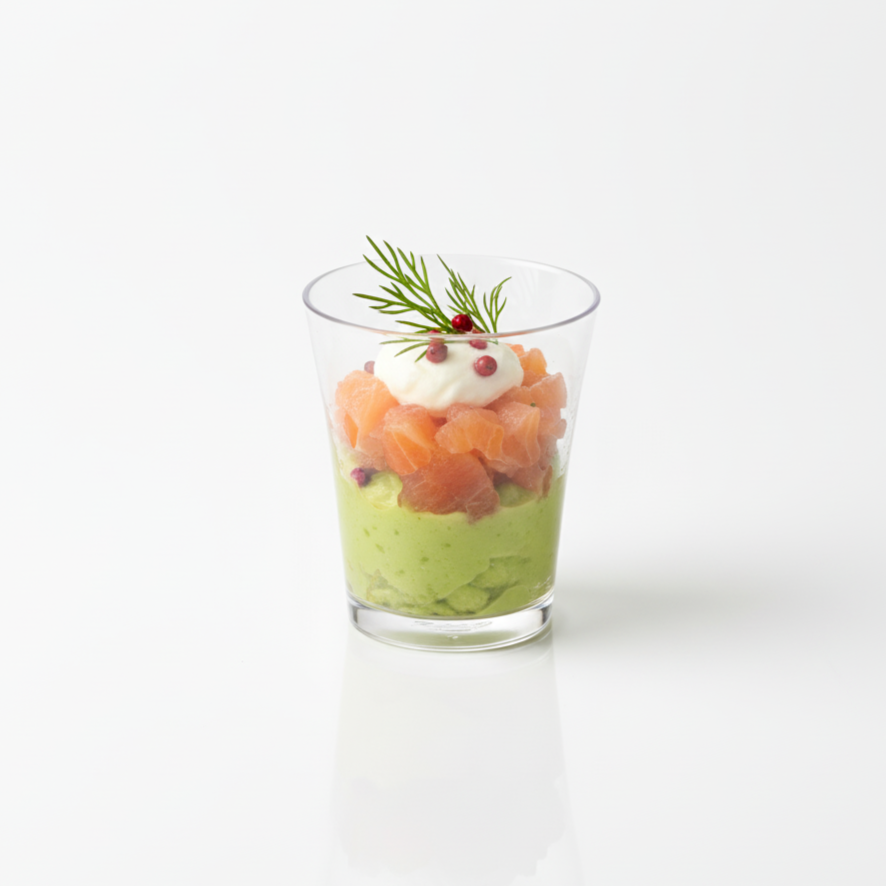 Verrine gastronomique au saumon et à l'avocat servie dans un verre transparent réutilisable de 5 cl sur fond de studio.
