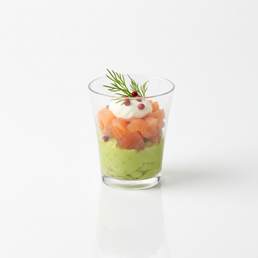 Verrine gastronomique au saumon et à l'avocat servie dans un verre transparent réutilisable de 5 cl sur fond de studio.